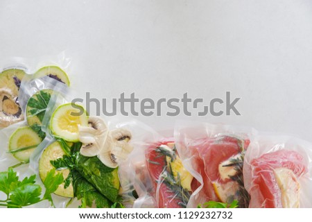 Fillet and vagatables in vacuum bags for sous vide coocing on white marbleized background Royalty-Free Stock Photo #1129232732