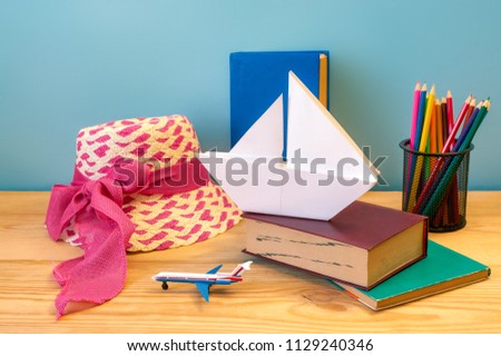 white paper ship, toy plane and book on wooden background. Concept travel