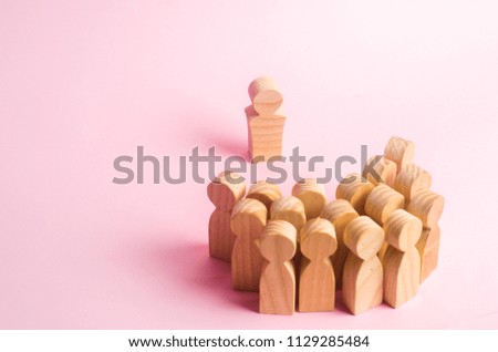 The crowd of wooden figures of people stand distantly and look at the leader. The person tries to establish contact with the group. business leader, company management