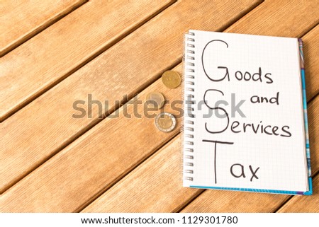 Goods and services and tax . GST inscription in Notepad on wooden background 