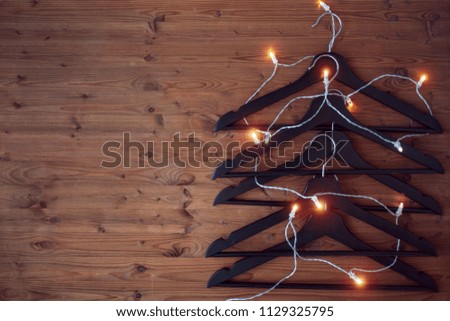 Christmas tree from hangers. Decorated with a luminous garland. A concert of Christmas sales. Textured wooden background