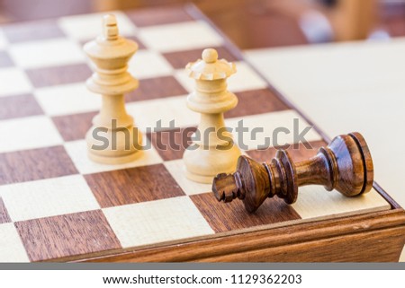 chess game. abstract composition of chess figures in chessboard isolated on light background. white queen and king win black king. two's company. three's a crowd