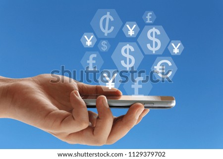 Hand of a businessman holding a smartphone and a financial symbol on blue background for design in your work concept.