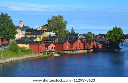 Ancient wooden houses on the river bank in the center of Porvoo in Finland at sunset in summer against the blue sky with clouds