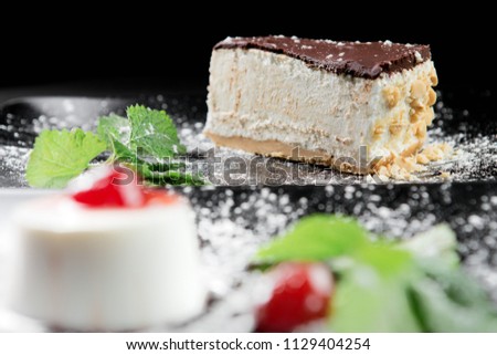 Photo of cake with nuts and mint leaf on the black wooden background.
