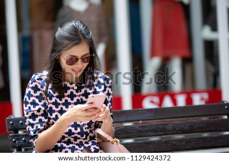 Asian woman in sun glasses is using a smart phone at the shopping center