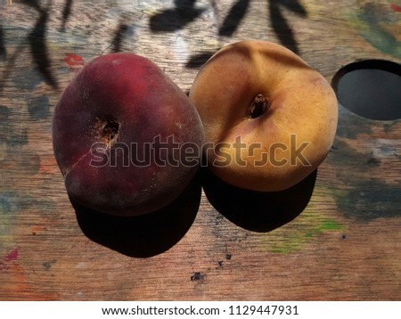 Prunus persica. Yellow red fruit peach on a glass transparent plate. Wooden background. A bright sunny day.
