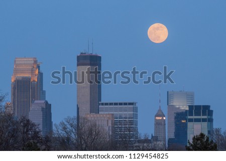 A Telephoto Shot Compressing the Skyscrapers of Downtown Minneapolis with a Full Moon Rising during Twilight in the Spring