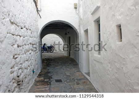 A view of a narrow street with arch and a scooter in the Greek island architecture of Patmos in summer