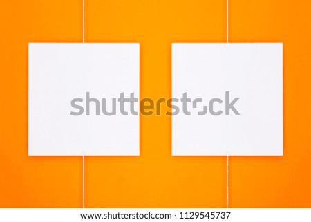 Paper cards (photo frame) hanging on metal rope with magnets on orange background