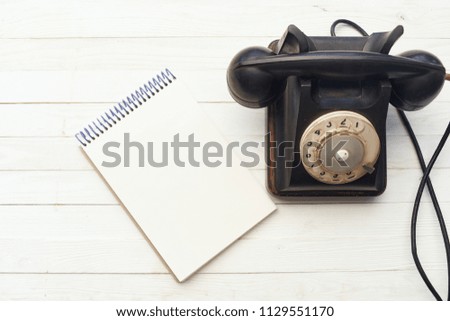 notebook and wire telephone on a wooden table                             