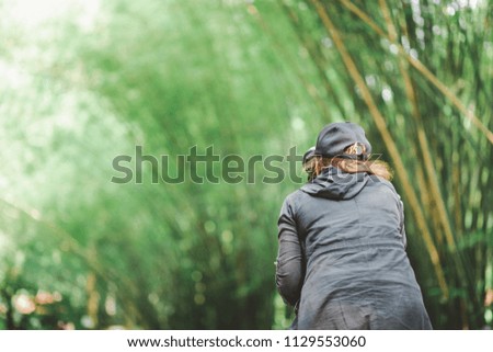 Professional female photographer with dslr camera and tripod taking photo in forest, summer green nature background
