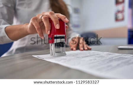 girl in the office puts a stamp on the documents Royalty-Free Stock Photo #1129583327
