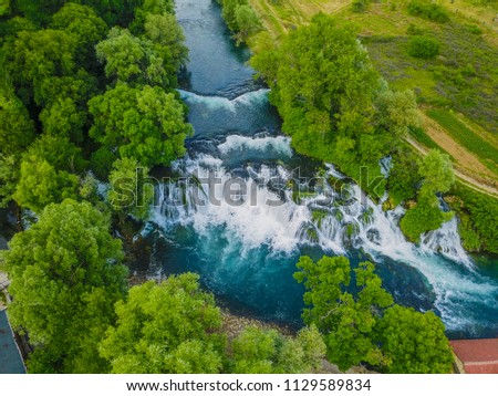 Koćuša Waterfall is situated in southern Bosnia and Herzegovina, and it is one of the most beautiful nature pearls in the region. The height of the tufa waterfall is 5 m and the length is 50 m. Royalty-Free Stock Photo #1129589834
