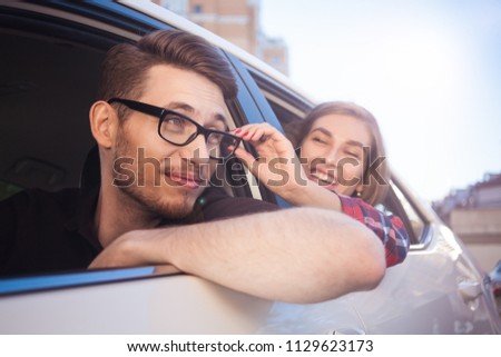 Enjoying travel. Beautiful young couple sitting on the front passenger seats and smiling while handsome man driving a car.