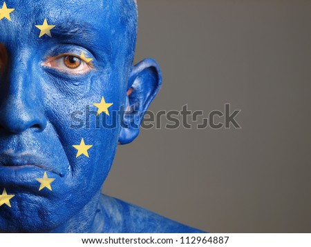 Man with his face painted with the flag of European Union. The man is sad and photographic composition leaves only half of the face.