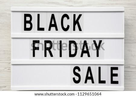 'Black friday sale' word on lightbox over white wooden surface, top view. From above, overhead.