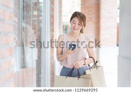 Asian Thai Elegant brown girl in blouse in cafe holding mobile phone and credit-card signing up on a website application. Businesswoman paying with a credit card while shopping online by smartphone