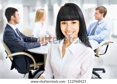 Successful asian business woman with her staff in background at office