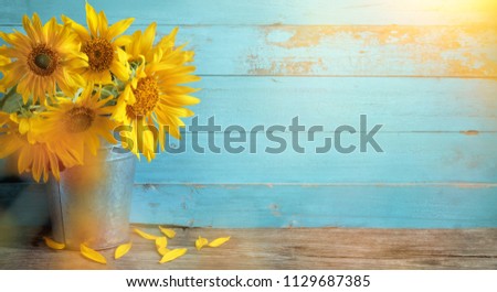 Sunflower flowers in rustic vase on wooden table and rustic background