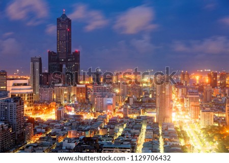 Nightscape of Kaohsiung City, a vibrant seaport in South Taiwan, with the landmark 85 Sky Tower standing among modern buildings, street lights dazzling in blue twilight and ships parking in the harbor Royalty-Free Stock Photo #1129706432