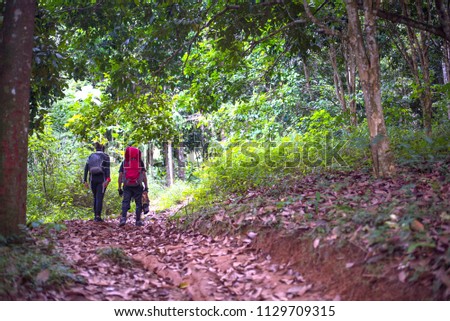 A couple hiking and walking into forest with their baggage to the top of mountains on holiday to Mt.Gunungsilipat, Yala province Thailand Royalty-Free Stock Photo #1129709315