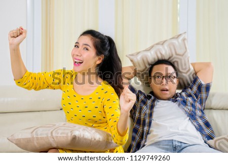 Picture of young man getting unhappy while watching a movie with his wife at home 