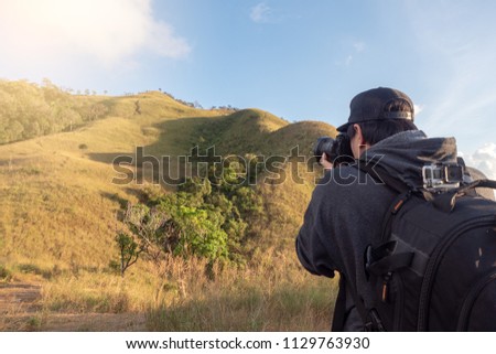 Asian guy backpacker Stand up to take pictures and enjoy the high mountain and forest atmosphere. Before going camping, enjoy the holidays.
