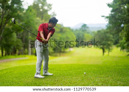 Asian golfer hitting golf ball on tee in golf course. It beautiful field for playing on mountain. Player happy and playful for this shot. This sport is exercise and hobby for lifestyle business man