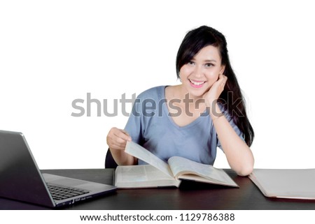 Picture of Caucasian female college student smiling at the camera while studying in the studio