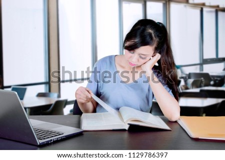 Picture of Caucasian female college student looks bored while studying in the classroom