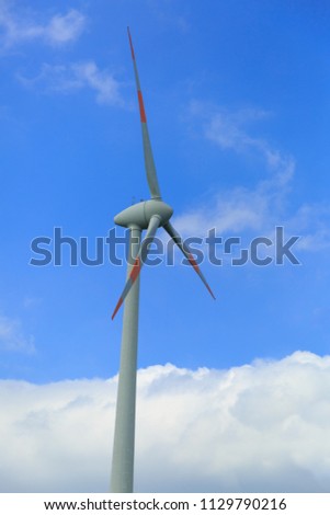 Electric Wind Turbine Windmill Wind Mill on the Background of Blue Sky and White Clouds