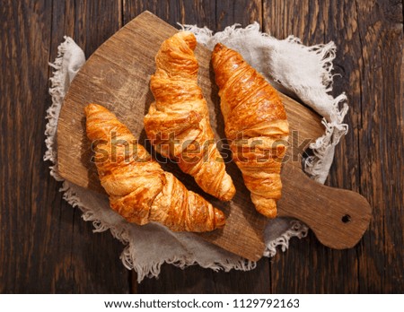fresh croissants on a wooden board, top view