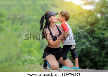 Young mother wear sport cloth kiss her son boy at nature outdoors.Concept image healthy family.