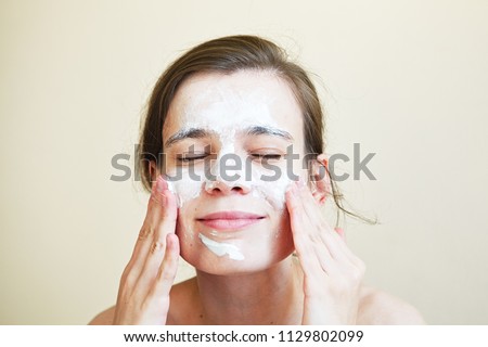 pretty young woman with clay mask on her face, facial care Royalty-Free Stock Photo #1129802099