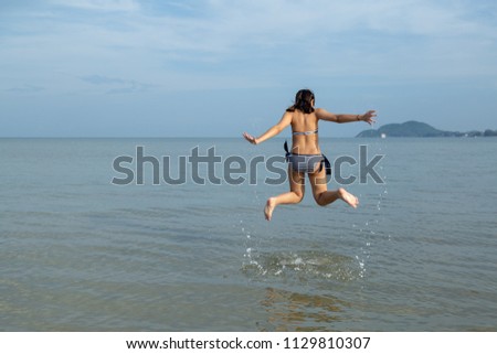 Asia teenage girls wearing bikini at the beach and jump up into the air with copy space.