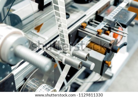 Automatic labeling machine. The labeled tape is located between the feed rollers. Royalty-Free Stock Photo #1129811330
