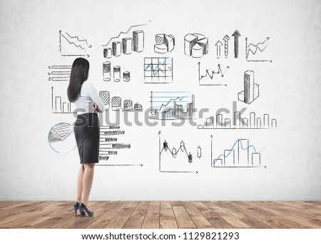 Businesswoman wearing a skirt and a shirt with high heels looking at infographics with bar charts and diagrams, business icons drawn on a concrete wall. Data representation concept