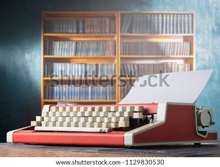Red vintage typewriter on the background of a bookshelf