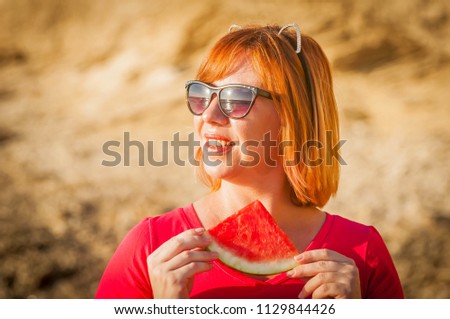 Beautiful Caucasian girl with funny ears eating watermelon with enjoyment. Summer vacation fun stock image. Happiness, weekend picnic.  