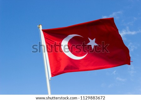 Perspective shot of colorful waving turkish flag with blue open sky background at Izmir in Turkey