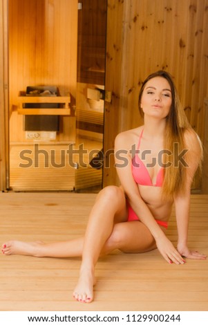 Young woman relaxing in wooden finnish sauna. Attractive girl in bikini resting. Spa wellbeing pleasure. Healthy lifestyle.