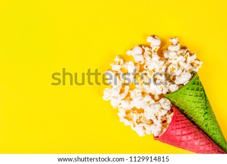 Spattered popcorn on yellow background. Two cups of popcorn on  yellow background. Holiday sweets. Festive decorations. Сopy space