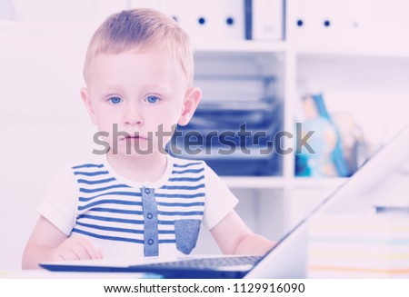 Young kid is surfing in internet on laptop in the office.