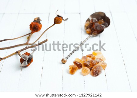 herbal tea leaves with dried rose hips, brown sugar and lemon on white wood table background
