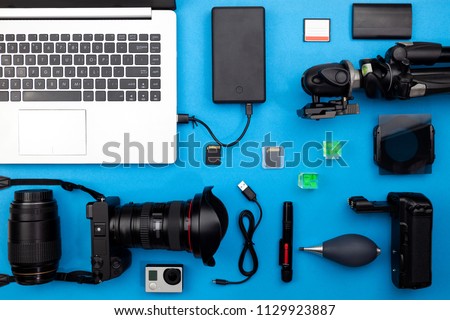 Digital camera with lenses and equipment of the professional photographer on blue paper background