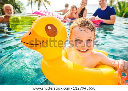 Boy swimming in a pool with family Royalty-Free Stock Photo #1129945658
