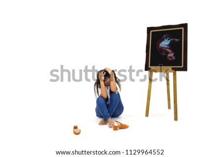 Young women sit on the floor with their hands on their head.Brown shoes are placed next to.Picture of Fighting fish (Betta splendens)  in frame on wooden stand.In the fish gallery isolated on white 