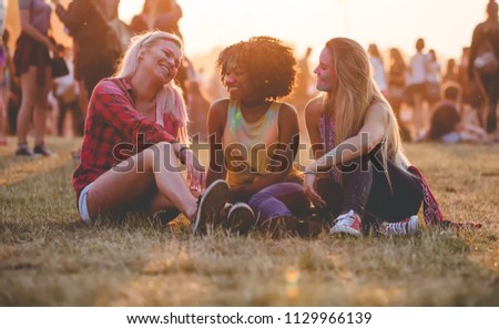 Young multiethnic girls sitting together at summer holi festival