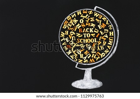 A chalk-drawn globe containing wooden letters of the English alphabet and an inscription Back to school on a chalkboard. The concept of study, school, sales.